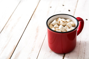 Christmas cocoa with marshmallow in mug on white wooden table. Copyspace