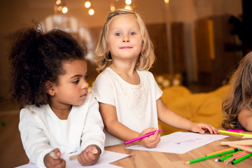 adorable multicultural children drawing together in kindergarten