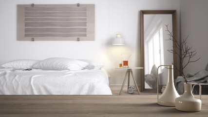 Wooden table top or shelf with minimalistic modern vases over blurred whit minimalist bedroom with double bed, white architecture interior design
