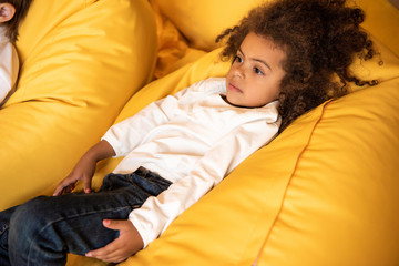 high angle view of adorable african american kid lying on bean bag chair in kindergarten