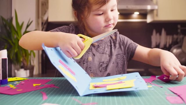 Crane shot. Scrapbooking. Little girl glueing colored paper. Children's creativity, handicraft