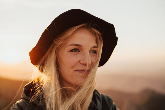 Portrait of beautiful young hipster woman watching sunset on the top of the mountain