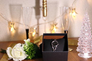 プレゼントの腕時計とシャンパングラスとクリスマスツリーとキャンドル	