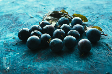 many fresh plums on blue background close up