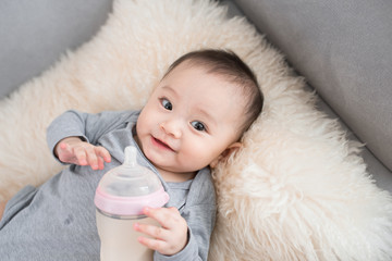 Asian baby infant eating milk from bottle, 9 months after birth