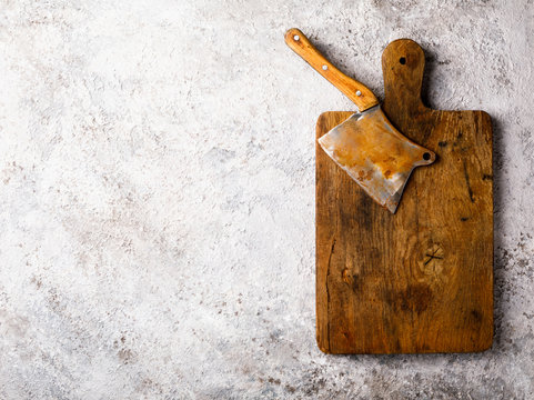 Vintage Kitchen Ax for felling Meat on a wooden board.Knife, Ceaver, Cutter with wooden Handle. Concept on a gray background. Top View. Copy space for Text.