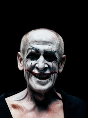 Bloody Halloween theme: The crazy smiling maniak face on dark studio background