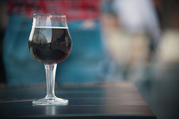 Glass of wine is on the table. The glass reflects the city street