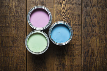 Pastel paint tins on wooden floorboards.
