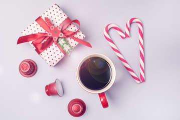Red Cup of Coffee Christmas Candy Canes in Shape of Heart Christmas Present Red Coffee Capsules Flat lay Top View Christmas Food Concept Toned