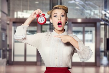 Shocked woman with alarm clock on blurred