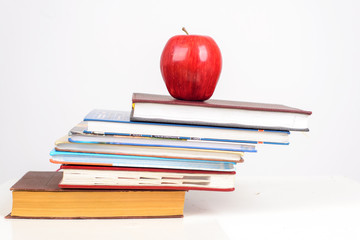 ripe Apple on the multi-colored books on table on white background