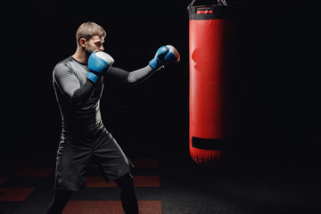 Male boxing in punching bag. Training man in gym.