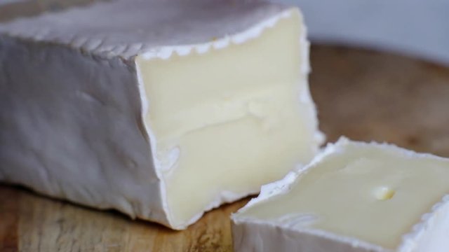 Cutting soft cheese, french brie or camembert, macro shot