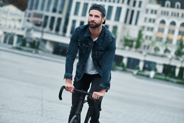 Outdoors leisure. Young stylish man on city street riding bicycle smiling happy
