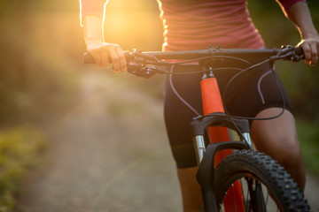 Pretty, young woman biking on a mountain bike enjoying healthy active lifestyle outdoors in summer (shallow DOF)