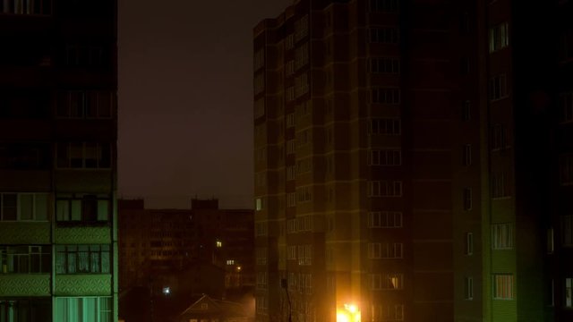 Residential houses with a switch on and off the light in the windows at night, timelapse. View through the windowpane