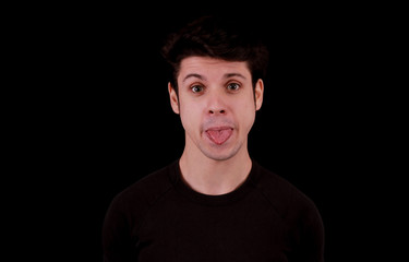 Muscular handsome young man pulling his tongue out with black tee shirt in front of black background