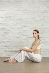 Portrait of young beautiful woman in casual cotton outfit sitting on the floor in the studio