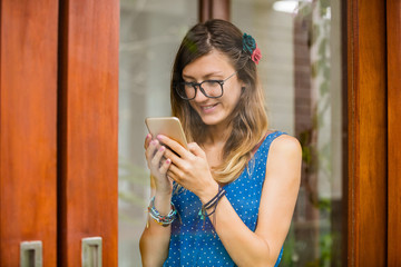 Young woman using smart phone indoors. Window reflection from outdoors.