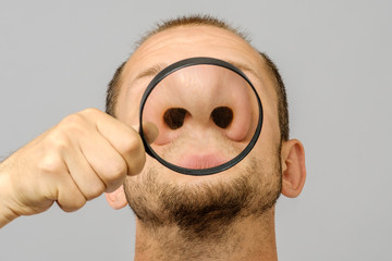 Portrait of caucasian man with magnifier makes fun face