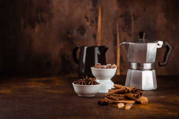 Coffee pot with spices on brown background.