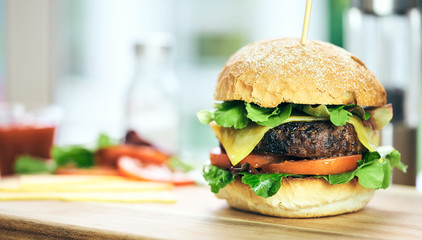 A cheese burger in a crusty bun with lettuce and tomatoes on a c