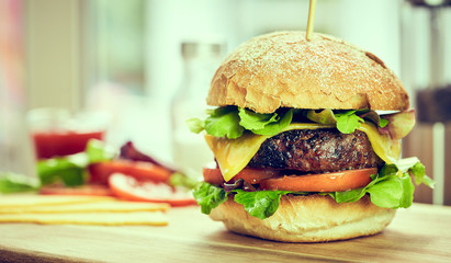 A cheese burger in a crusty bun with lettuce and tomatoes on a c