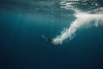 Underwater swimmer in sea with air jet bubbles tail against dark water background