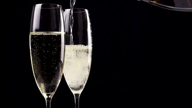 Two glasses of champagne with bottle on black background. Close up.
