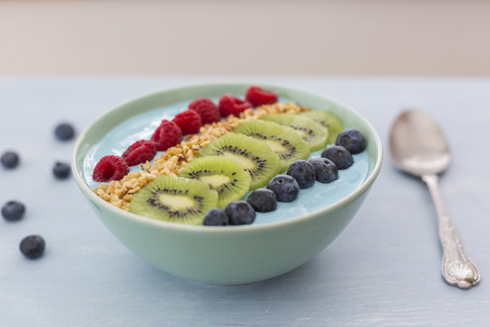 Smoothie bowl with blueberries, raspberries, kiwi and chopped hazelnuts