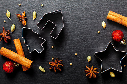 Holiday Food background Christmas cookies cutter spices Star anise, cloves and cadamon pods on black slate board