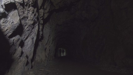 view deep cave with figures of two people with lanterns