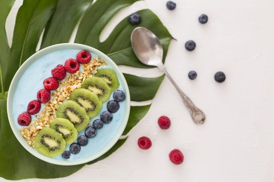 Smoothie bowl with blueberries, raspberries, kiwi and chopped hazelnuts