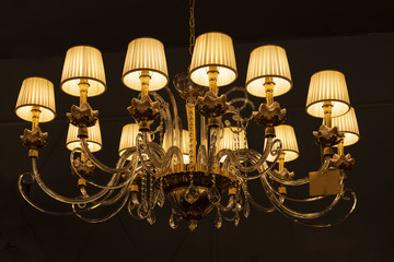Beautiful expensive royal chandelier hanging at the ceiling in the dark room