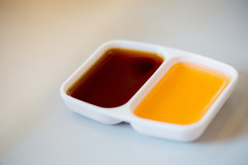 Close up two color tone of chinese sour and sweet sauce in white cup for dimsum. Color of food, fill up tasty concept.