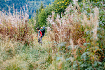 Obraz premium A sporty american man carries a child in a backpack. Dad is traveling with a child. Hiking with the baby. Parent lead an active lifestyle. The boy is on his father's back.