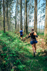 Young woman and man participating in a trail race through the forest