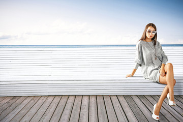 Fototapeta na wymiar Slim young woman on wooden pier and autumn landscape of sea 