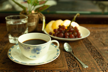 Morning light with coffee cup and glass of water and fresh fruit