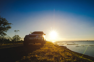 Businessmen with SUV cars parked on the road along the reservoir. Watching the sunset