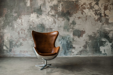 Loft interior mock up photo. Gray textured wall with leather armchair. Background photo with copy...