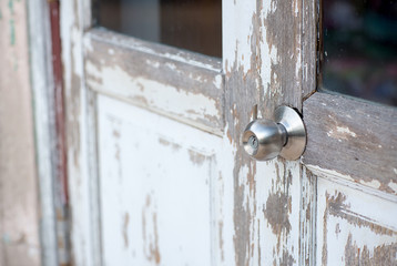 Door with grill, stainless door knob or handle on wooden door in beautiful lighting.a handle on a door that is turned to release the latch.