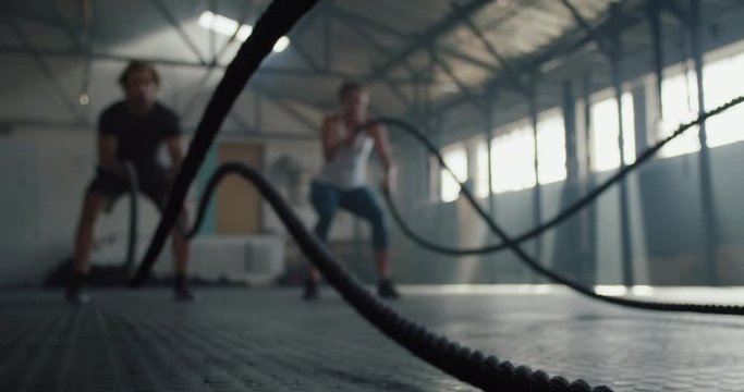 fitness athletes training using battle ropes intense workout team exercise challenge in gym friends enjoying healthy bodybuilding endurance practice lifestyle together slow motion