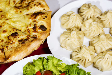 A table with dishes of khinkali and khachapuri. Close-up photo. The concept of traditional Georgian national cuisine.