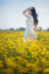 Fototapeta premium pretty woman in the white dress at yellow flowers field