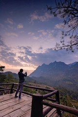 Fototapeta na wymiar Traveler taking photo of mountain in the morning with mobile phone