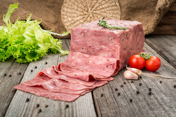 Cut sausage from ham on a wooden background
