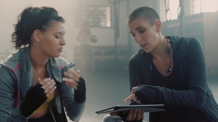 healthy woman using tablet computer fitness coach sharing performance results to female athlete enjoying workout motivation in gym meeting talking together
