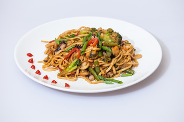 Wok food on a white ceramic plate is tasty and fresh with sauce on a light isolated background